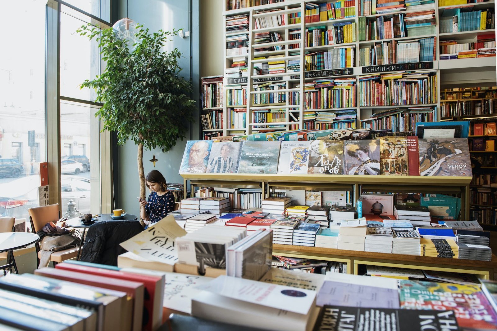 female customer using social media on smartphone sitting in bookstore